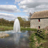 Image of Kasco 5HP Decorative Fountain 5.1JF 5.3JF 230V with Birch Pattern Operating in a Pond with Trees at the Back